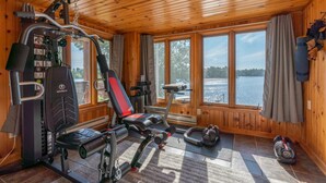 A gym with exercise equipment, large windows, and a view of a lake.