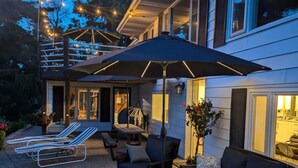 An outdoor patio area with lounge chairs, a sofa, and a large umbrella.