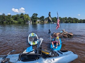 A kayak on a calm lake with a statue and an American flag in the background.