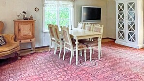 A dining area with a table and chairs, a television mounted on the wall, and a cabinet with decorative items. - 6 Person Holiday Home in Loftahammar (Loftahammar)