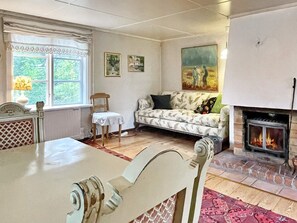 A cozy living room with a fireplace, a sofa, a dining table, and a chair. - 6 Person Holiday Home in Loftahammar (Loftahammar)