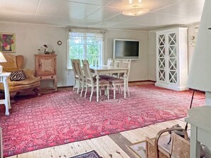 A dining area with a table and chairs, a television, and a cabinet.