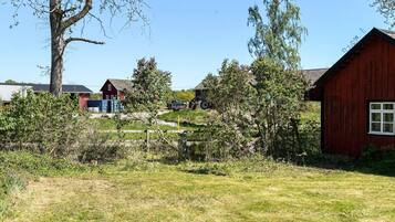 Een landelijk landschap met een rode schuur, een wit gebouw en een boom.