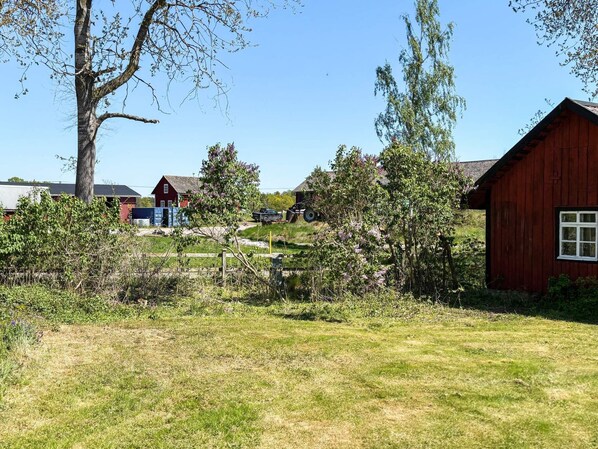 A rural landscape with a red barn, a white building, and a tree.