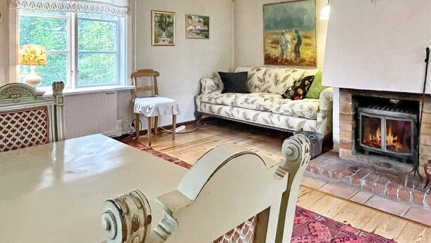 A cozy living room with a fireplace, a sofa, a dining table, and a chair. - 6 Person Holiday Home in Loftahammar (Loftahammar)