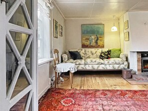 A living room with a patterned sofa, a painting on the wall, and a fireplace.