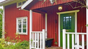 A red wooden house with a green door, white railings, and a small porch area. - 6 Person Holiday Home in Loftahammar (Loftahammar)