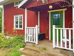 A red wooden house with a green door, white railings, and a small porch area. - 6 Person Holiday Home in Loftahammar (Loftahammar)