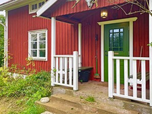 A red wooden house with a green door, white railings, and a small porch area. - 6 Person Holiday Home in Loftahammar (Loftahammar)