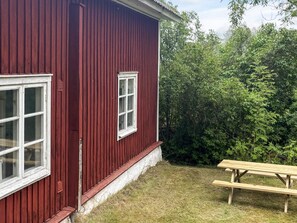 A red building with two windows and a wooden bench.