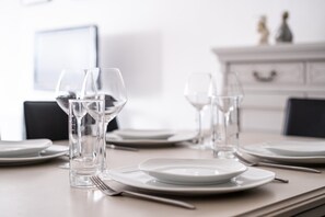 A neatly set dining table with white plates, clear glasses, and cutlery. - Apartment Near Belgian Coast Beach (Koksijde)