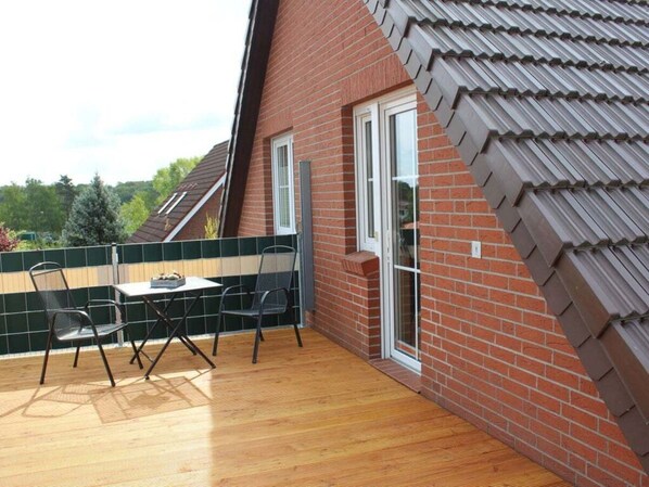 A patio with a table and chairs, a brick wall, and a tiled roof.