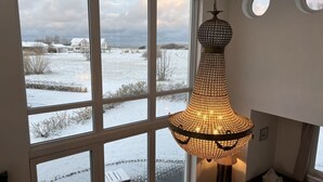 Huone, jossa on suuret ikkunat, riippuvalaisin ja näkymä lumiseen maisemaan.