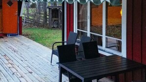 A covered patio with a table and chairs, a bicycle, and a wooden deck. - 8 Person Holiday Home in Hogklint-by Traum (Visby)