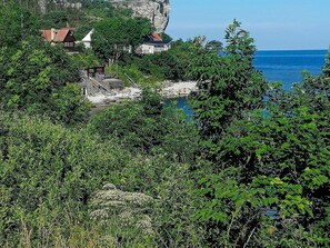 A coastal view with a cliff, houses, and dense greenery. - 8 Person Holiday Home in Hogklint-by Traum (Visby)