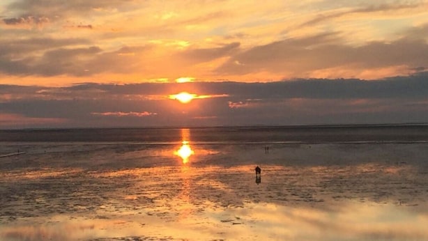 Um pôr do sol sobre águas tranquilas, com o horizonte nítido.