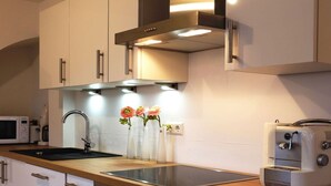 A modern kitchen with white cabinets, a stainless steel sink, a toaster, and a microwave. - Lake Constance Hearts (Meersburg)