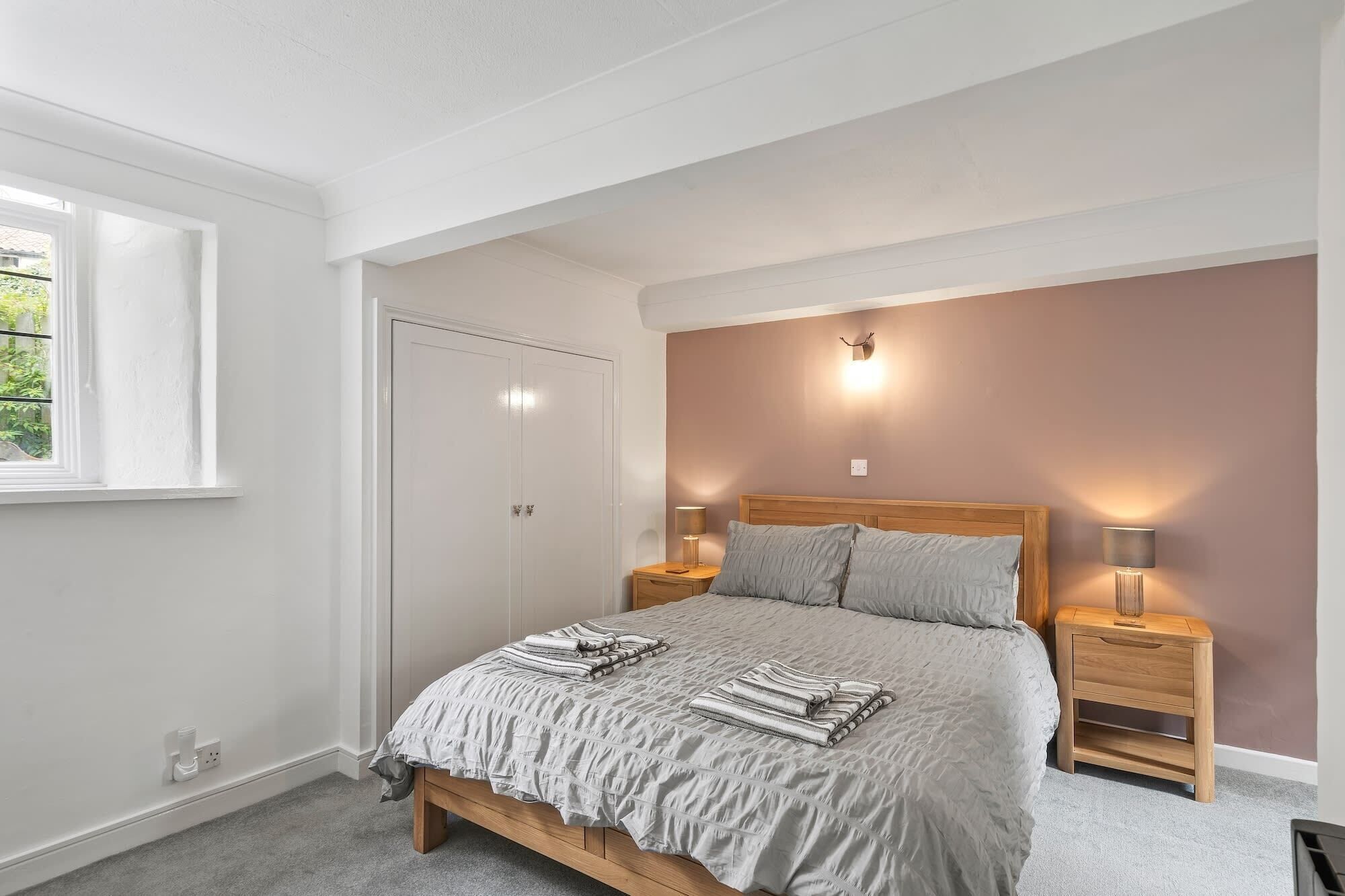 A bedroom with a bed, bedside tables, a window, and a door.