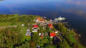 An aerial view of a coastal village with houses, a dock, and a ferry. - Kubis Modern Retreat (Wiek)