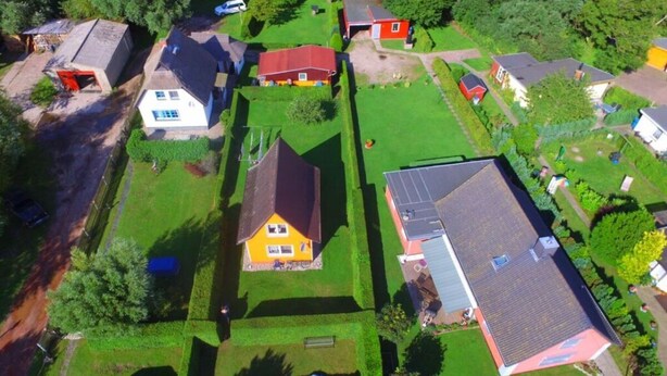 An aerial view of a residential area with houses, green lawns, and a solar panel on one house. - Kubis Modern Retreat (Wiek)