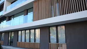 Un edificio moderno con ampie vetrate, un rivestimento in legno a listelli al piano superiore e un pavimento in mattoni.