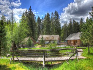 Eine rustikale Holzhütte, umgeben von einem Wald, mit einer Holzbrücke als Zugang.