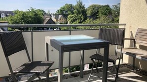 An outdoor balcony with a glass-top table and two wicker chairs. - Holiday Apartment New Love (Zingst)