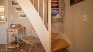 A staircase with a white handrail and wooden steps, leading to a landing with a small table and a chair. - Holiday Apartment New Love (Zingst)