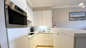 A compact kitchen with white cabinets, a stainless steel microwave, a coffee maker, and a sink. - Apartment in Nieuwpoort Near the Beach (Nieuwpoort)