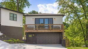 Une maison à deux étages avec un garage à l’avant, un balcon et une allée aménagée.