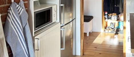 A kitchen with a microwave, oven, and refrigerator. There is a striped towel hanging on the wall and a rug on the floor.