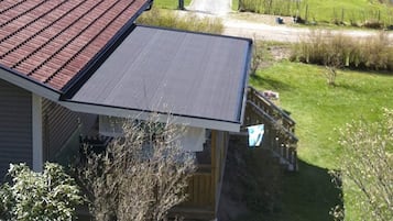A residential building with a sloped roof, a visible front porch, and a pathway leading to a parked car.
