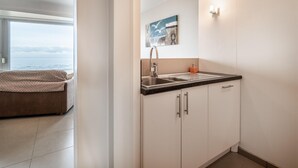 Eine moderne Küche mit Spüle, Schränken und einem Meerblick durch das Fenster.