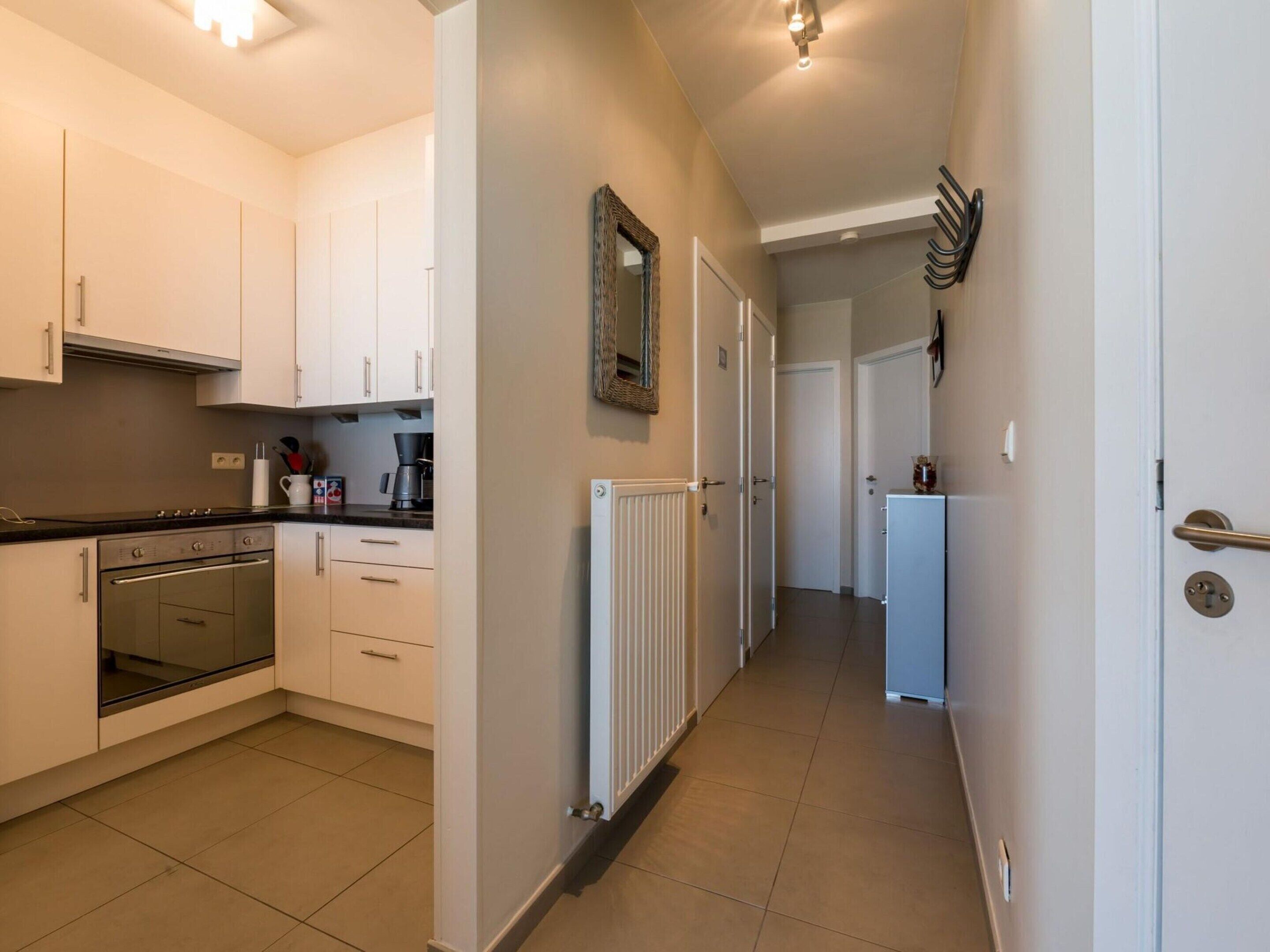 A modern kitchen with white cabinets, a built-in oven, and a coffee maker.