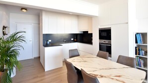Een moderne keuken met witte kastjes, een zwart aanrecht en een ingebouwde oven.