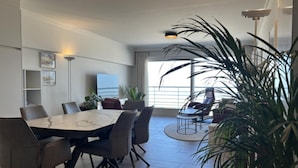Een moderne eetruimte met een marmeren tafel, comfortabele stoelen en uitzicht op de oceaan.