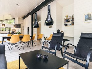 A modern living room with a black coffee table, yellow and black chairs, and pendant lights. - 7 Person Holiday Home in Albaek (Aalbaek)