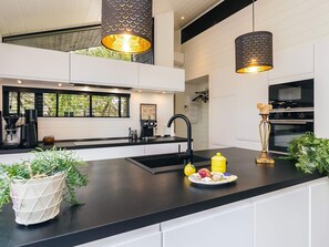 A modern kitchen with a black countertop, stainless steel appliances, and pendant lighting. - 7 Person Holiday Home in Albaek (Aalbaek)