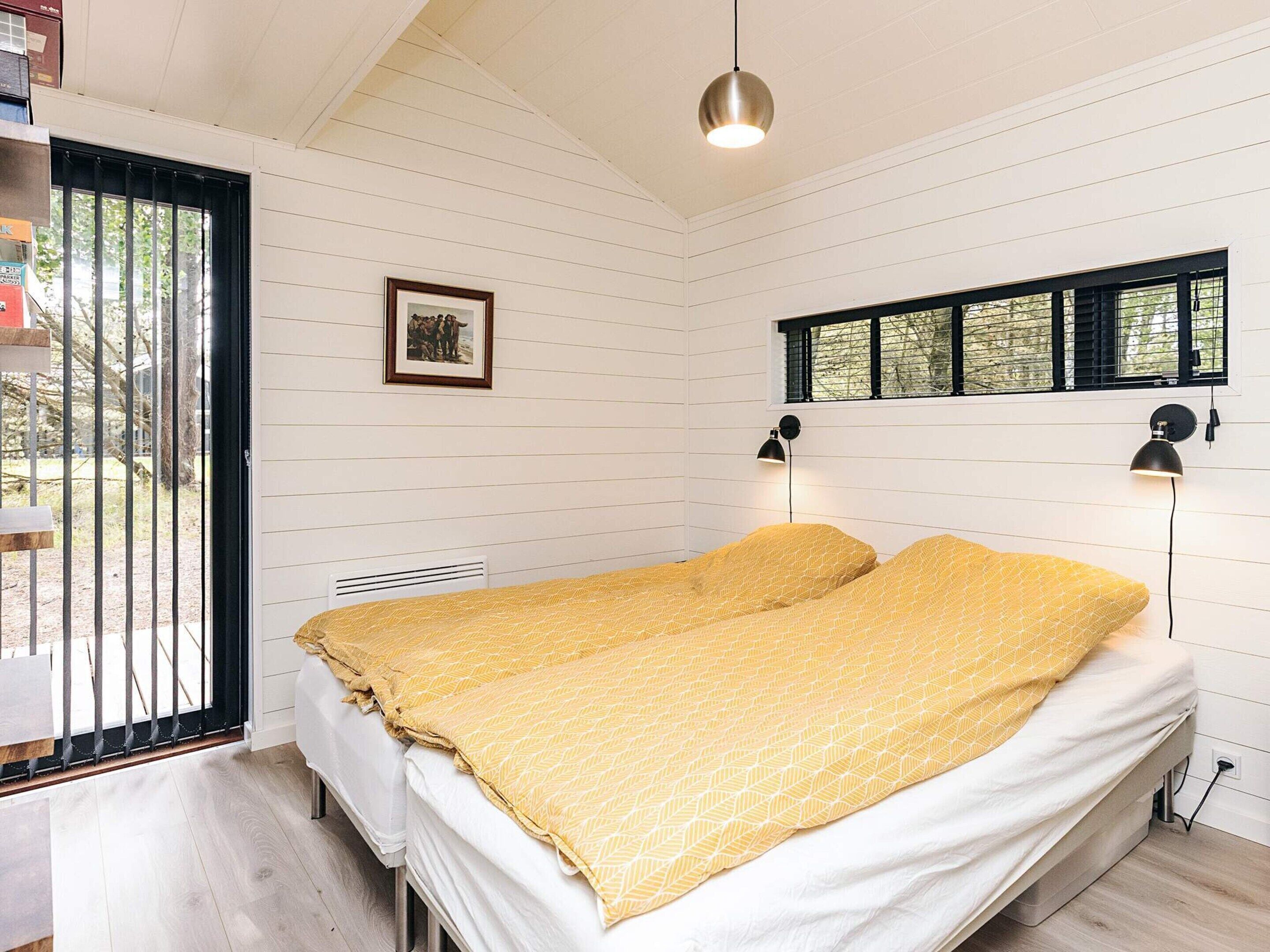 A bedroom with a bed, a window, and a picture on the wall.