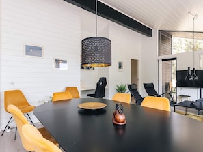 A modern meeting room with a large black table, yellow chairs, and a unique black pendant light. - 7 Person Holiday Home in Albaek (Aalbaek)