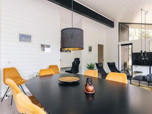 A modern meeting room with a black table, yellow chairs, and a unique black pendant light. - 7 Person Holiday Home in Albaek (Aalbaek)