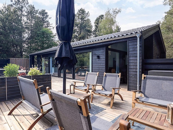 A wooden deck with outdoor furniture, a covered seating area, and a building with large windows. - 7 Person Holiday Home in Albaek (Aalbaek)