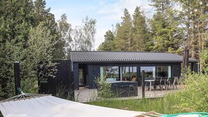 Une maison moderne dotée d’un patio, de grandes fenêtres et d’un hamac.