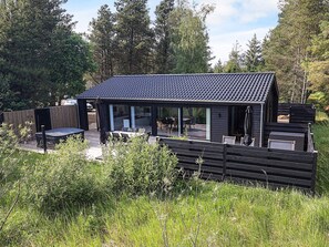 A modern outdoor patio area with a covered seating area, a barbecue grill, and a wooden deck. - 7 Person Holiday Home in Albaek (Aalbaek)