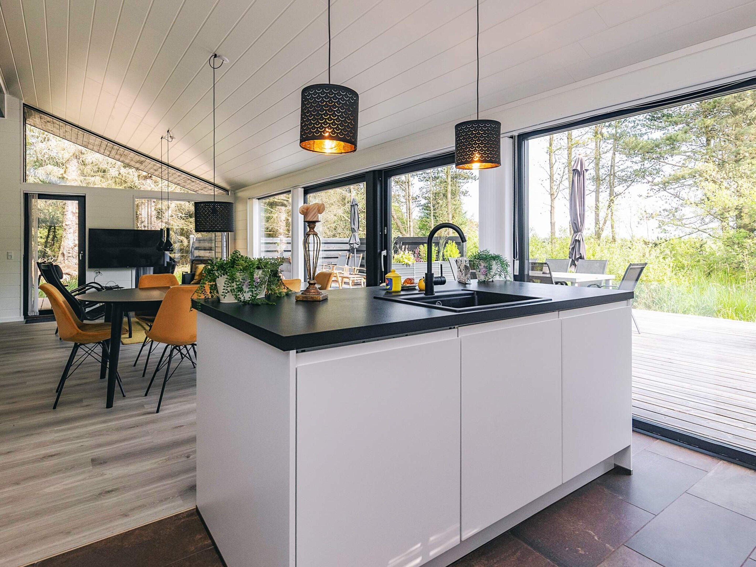 A modern kitchen with a large island, white cabinetry, and pendant lighting.