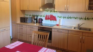 A compact kitchen with wooden cabinets, a microwave, a coffee maker, and a stove. - Ground Floor Palatine (Rumbach)