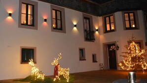 Un bâtiment doté de nombreuses fenêtres, dont certaines sont éclairées de l’intérieur. On y voit des décorations lumineuses en forme de rennes et un sapin de Noël.