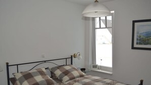 A single bed with a metal frame, a checkered bedspread, and two bedside lamps. - Holiday Apartment Windrose (Boergerende-Rethwisch)