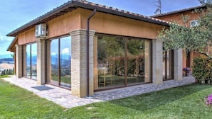 A house with a covered patio, large glass windows, and a stone foundation. - Villa Morotti Comfortable Holiday Residence (Montone)