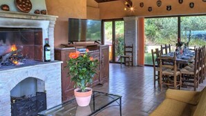 A spacious living area with a fireplace, a television, and a dining table set for six. - Villa Morotti Comfortable Holiday Residence (Montone)